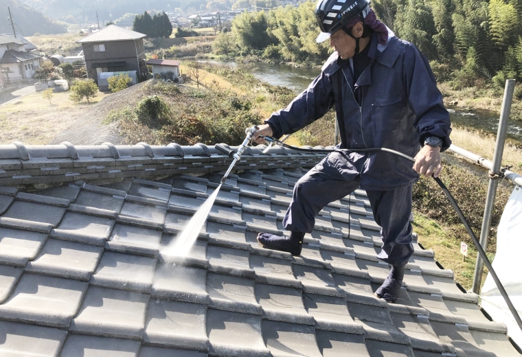 屋根の洗浄をする作業員